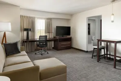 a hotel room with a couch and a desk and a television at Residence Inn by Marriott Denver Central Park in Denver