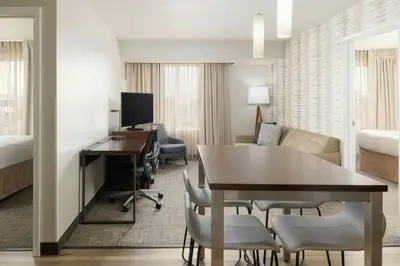 a hotel room with a desk and a dining room at Residence Inn by Marriott Denver Central Park in Denver