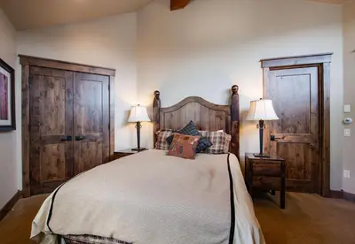 a bedroom with a bed with two lamps and two doors at The Shores Riverside Townhome: Peaceful Luxury in Breckenridge