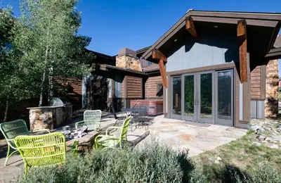 a patio with chairs and a grill in front of a house at The Shores Riverside Townhome: Peaceful Luxury in Breckenridge