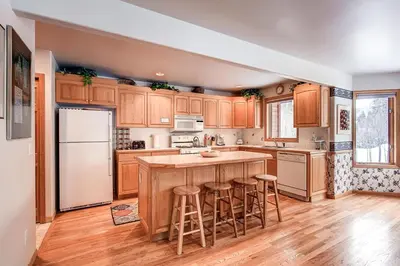 a kitchen with wooden cabinets and a island with bar stools at Village Townhome: Views, Location in Frisco