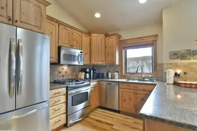 a kitchen with wooden cabinets and a stainless steel refrigerator at Mt. Victoria Lodge Penthouse Condo: Downtown, Hot Tub in Frisco