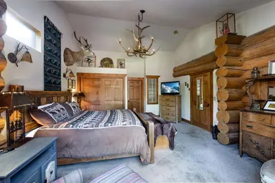a bedroom with a bed and a log wall at Swan River Lodge Home: Spacious, Hot Tub in Breckenridge