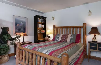 a bedroom with a wooden bed and a book shelf at Swan River Lodge Home: Spacious, Hot Tub in Breckenridge