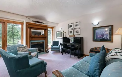 a living room with a blue couch and a piano at Swan River Lodge Home: Spacious, Hot Tub in Breckenridge