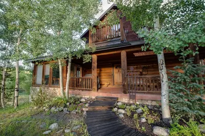 a log cabin with a wooden walkway in front of it at Swan River Lodge Home: Spacious, Hot Tub in Breckenridge