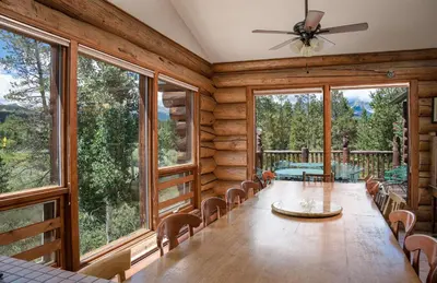 a dining room with a table and chairs and large windows at Swan River Lodge Home: Spacious, Hot Tub in Breckenridge