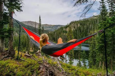 a woman laying in a hammock near a lake at Crossroads Snowshoe Townhome: Great Views, On Rec Path in Summit Medical Center Heliport