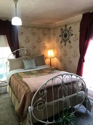 a bedroom with a metal bed with floral wallpaper at Historic Windsor in Silver Plume