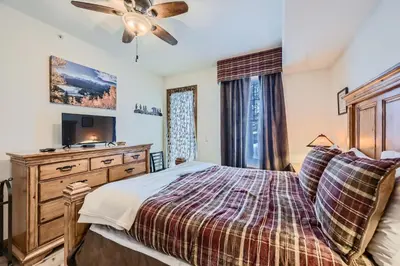 a bedroom with a bed and a dresser with a tv at Highland Greens Lodge 210 Colorado in Breckenridge