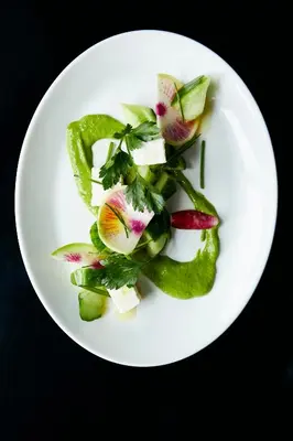 a white plate of food with vegetables on a table at Limelight Hotel Denver in Denver
