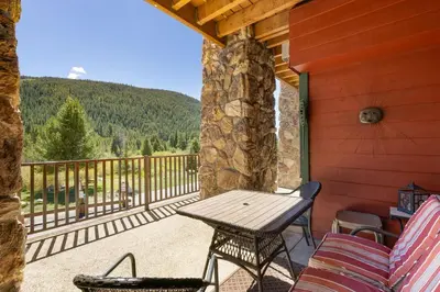 a patio with a wooden table and chairs on a porch at 5949 Hidden River Lodge Condo in Keystone