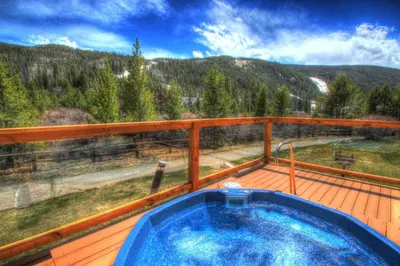a hot tub on a deck with a view of the mountains at Ffd7 Frostfire Condo in Keystone