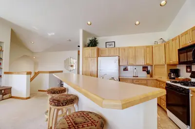a kitchen with wooden cabinets and a counter with stools at 172 Sauterne Sanctuary Townhouse in Silverthorne