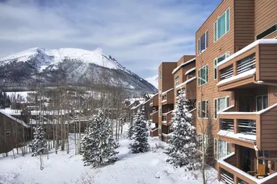 a building in the snow with a mountain in the background at 522 Watch Hill Condo in Silverthorne