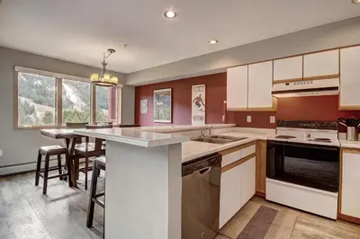 a kitchen with white cabinets and a large island at C213 Cinnamon Ridge Condo in Keystone