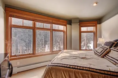 a bedroom with a bed and two windows with trees at 3044 Lone Eagle Condo in Keystone