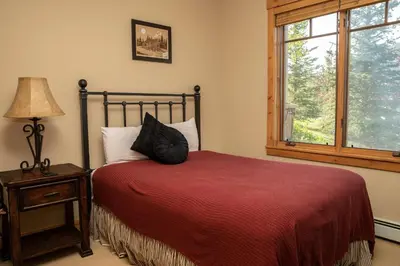 a bedroom with a bed and a lamp and a window at 6532 Settlers Creek Condo in Keystone