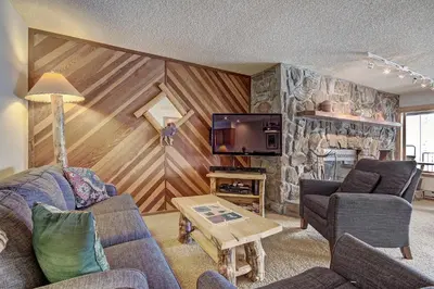 a living room with couches and a stone wall at Cri221 Cinnamon Ridge Condo in Keystone