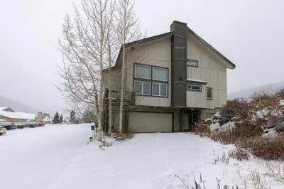 a house with a garage in the snow at 130 Meisel Drive Townhouse in Keystone