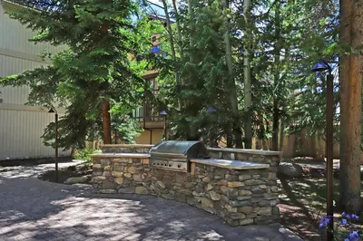 a stone fire pit in a yard with trees at 2721 Chateaux DMont Condo in Keystone
