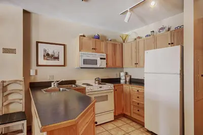 a kitchen with a white refrigerator and wooden cabinets at 8493 Dakota Lodge Condo in Keystone
