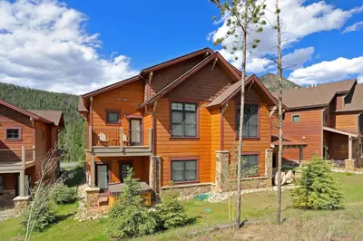 a large wooden house with a mountain in the background at 78 Alders Townhouse with Heated Garage in Keystone