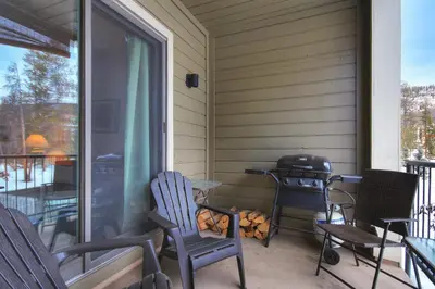 a screened in porch with two chairs and a grill at 2062 The Pines Condo in Keystone