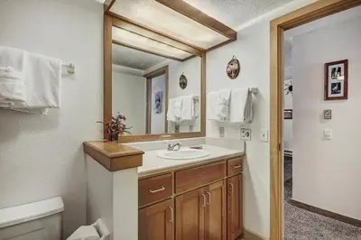 a bathroom with a sink and a toilet and a mirror at 2062 The Pines Condo in Keystone