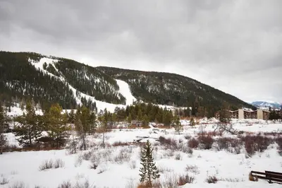 a snow covered mountain with a building and a bench at C212 Cinnamon Ridge Condo in Keystone