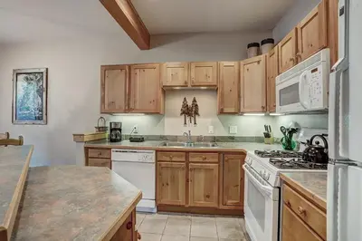 a kitchen with wooden cabinets and white appliances at 8757 Trappers Crossing Condo in Keystone