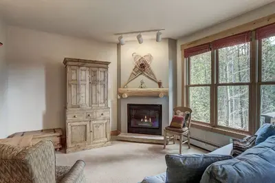 a living room with a fireplace and a blue couch at 8757 Trappers Crossing Condo in Keystone