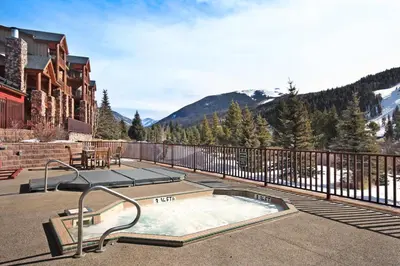 a hot tub on a patio with mountains in the background at 5983 Hidden River Lodge Condo in Keystone