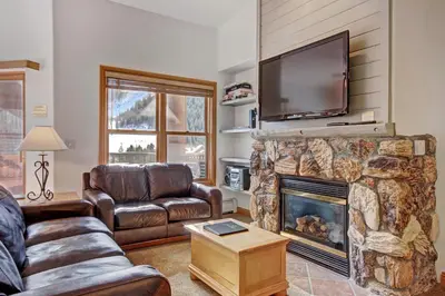 a living room with a couch and a fireplace with a flat screen tv at 5983 Hidden River Lodge Condo in Keystone