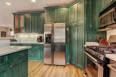 a kitchen with green cabinets and a stainless steel refrigerator at 201 Mill Creek Condo in Keystone