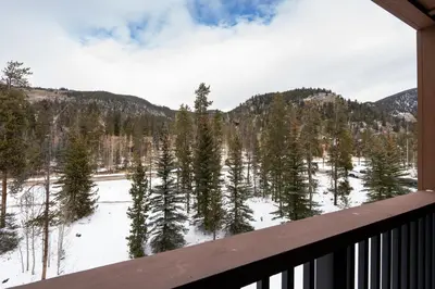 a view from a balcony of a snow covered forest at 8858 The Springs Condo in Keystone
