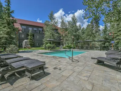 a swimming pool with benches and a building at 8594 Expedition Station Condo in Keystone