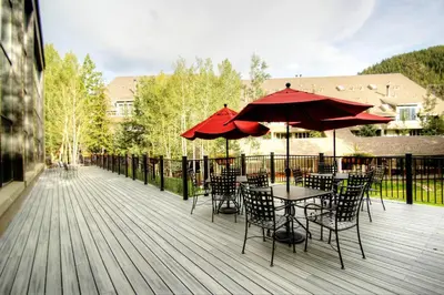 a deck with tables and chairs with red umbrellas at 2130 Pines Condo in Keystone