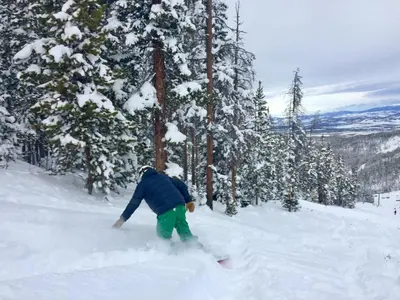 a person riding a snowboard down a snow covered slope at A11 Snowblaze Athletic Club Condo in Winter Park