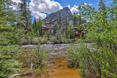 a house in the middle of a river with a mountain at Ten Mile Island 119C Condo in Frisco