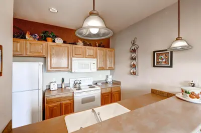 a kitchen with wooden cabinets and a white refrigerator at Tarn Landing C-5 Condo in Frisco