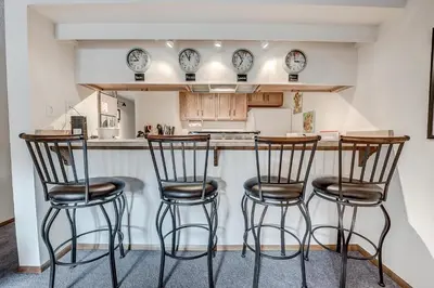a kitchen with three bar stools and clocks on the wall at Mountainside 229E Condo in Frisco
