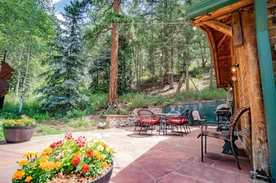 a patio with a table and chairs and flowers at Colorado Bear Creek Cabins in Evergreen