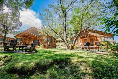 a log cabin with picnic tables in the grass at Colorado Bear Creek Cabins in Evergreen