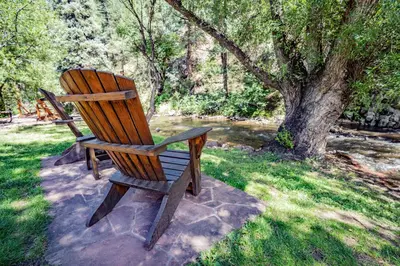 a wooden chair sitting in the grass next to a tree at Colorado Bear Creek Cabins in Evergreen