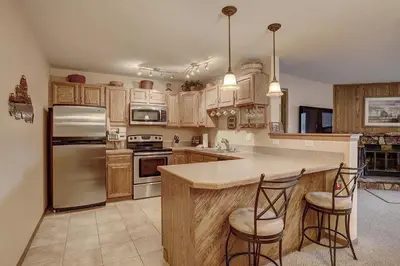 a kitchen with wooden cabinets and stainless steel appliances at 204 Snowdance Manor Condo in Keystone