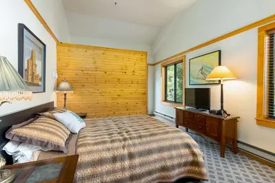a bedroom with a bed and a table and two lamps at Penthouse 2796 Slopeside Ski In Ski Out Condo in Keystone