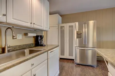 a kitchen with a stainless steel refrigerator and white cabinets at 2964 Key Condo in Keystone