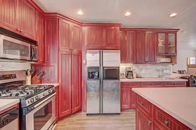 a kitchen with red wooden cabinets and a refrigerator at River Run Mill Creek Combo Condo in Keystone