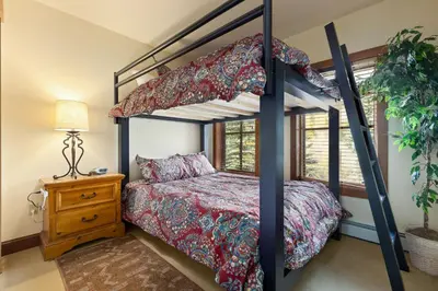 a bedroom with a bunk bed with a red bedspread at 201 Oro Grande Condo in Keystone